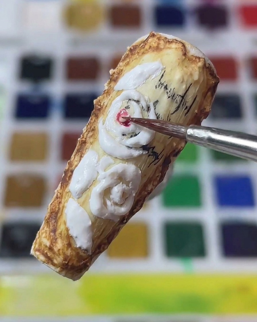 Nahaufnahme eines feinen Nail-Art-Pinsels, der rotes Pigment auf die Mitte der weißen 3D-Rosen auf einem Vintage-Nagel aufträgt.