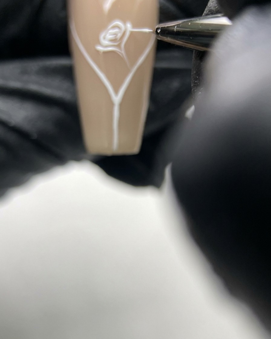 Ein Nagel mit einem fertigen Rosendesign, bei dem ein dünner Stiel zur Nagelspitze verläuft.
