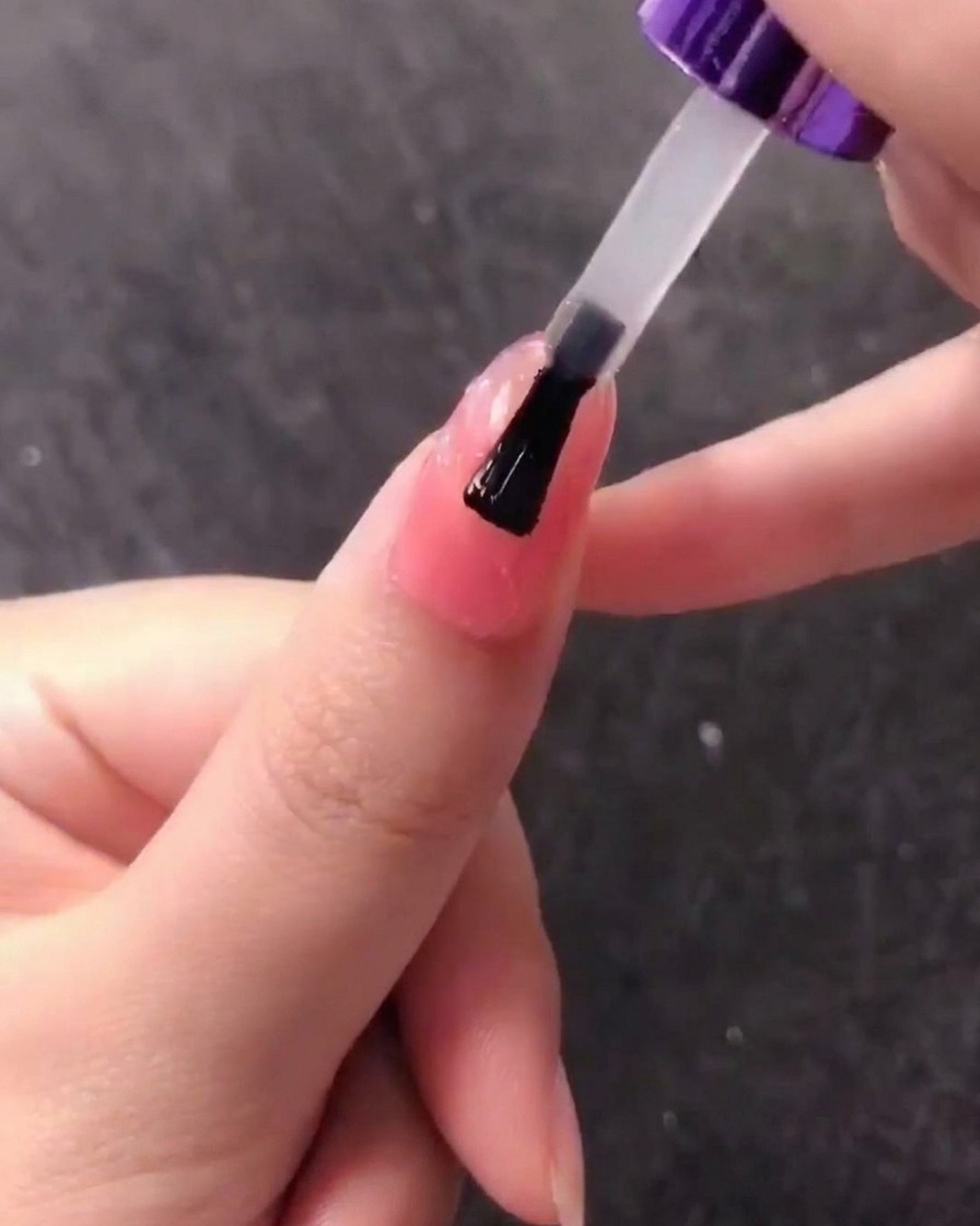 Ein Pinsel trägt eine Schicht klares Gel über dem strukturierten Muschelnageldesign auf.