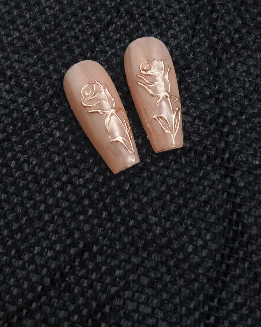 Ein feiner Nailart-Pinsel zeichnet mit transparentem, erhabenem Gel eine Rosenform auf einen nuden Nagel.