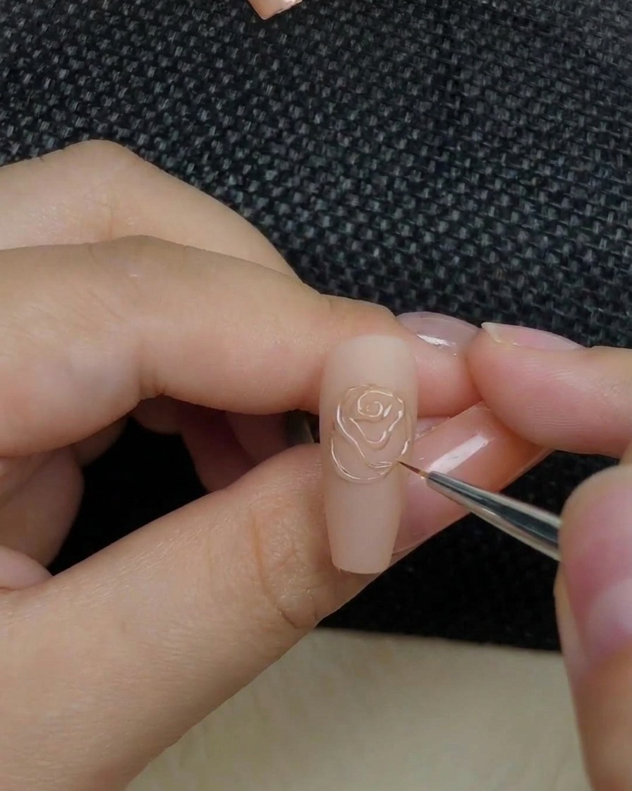 Eine Hand platziert einen Nagel mit erhabenem Rosendesign in einer UV-Lampe.