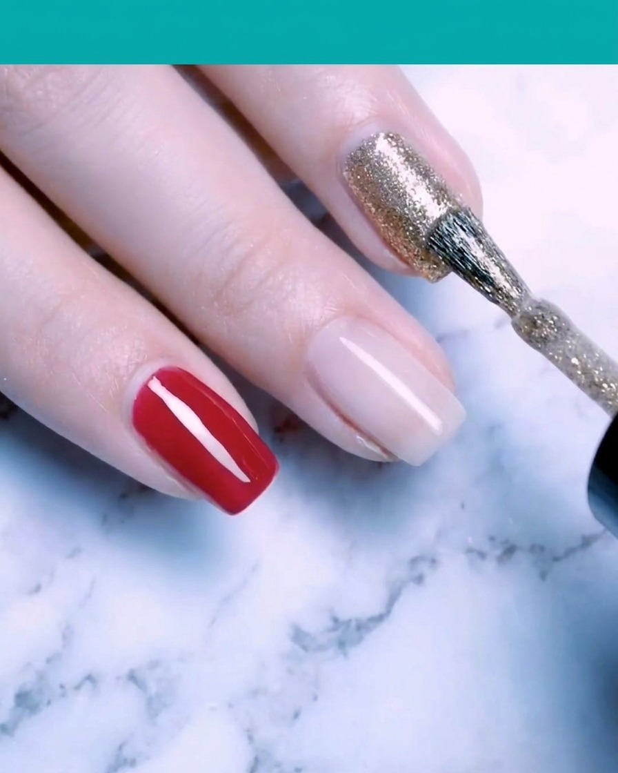 Ein Pinsel trägt funkelndes, feines Goldglitzer-Gel auf einen Fingernagel auf.