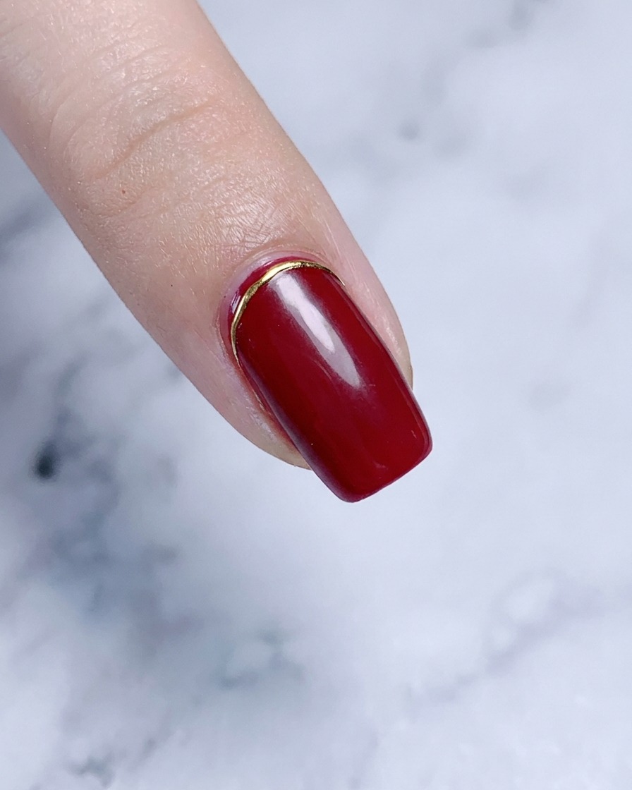 Ein Zeigefinger mit einem eleganten Gold-Element an der Nagelhautlinie.