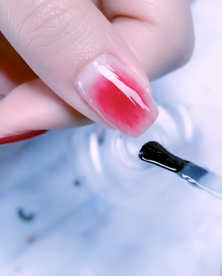 Nahaufnahme eines Daumennagels, verziert mit Blattgold, Metalldraht und Perlen über einem Roségold-Verlauf.