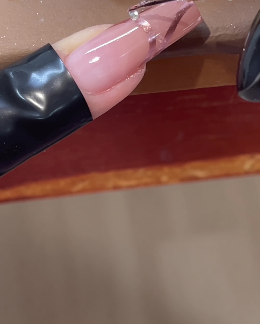 Platzieren eines kleinen klaren Strasssteins auf eine 3D-Chrome-Linie mit einem Werkzeug.