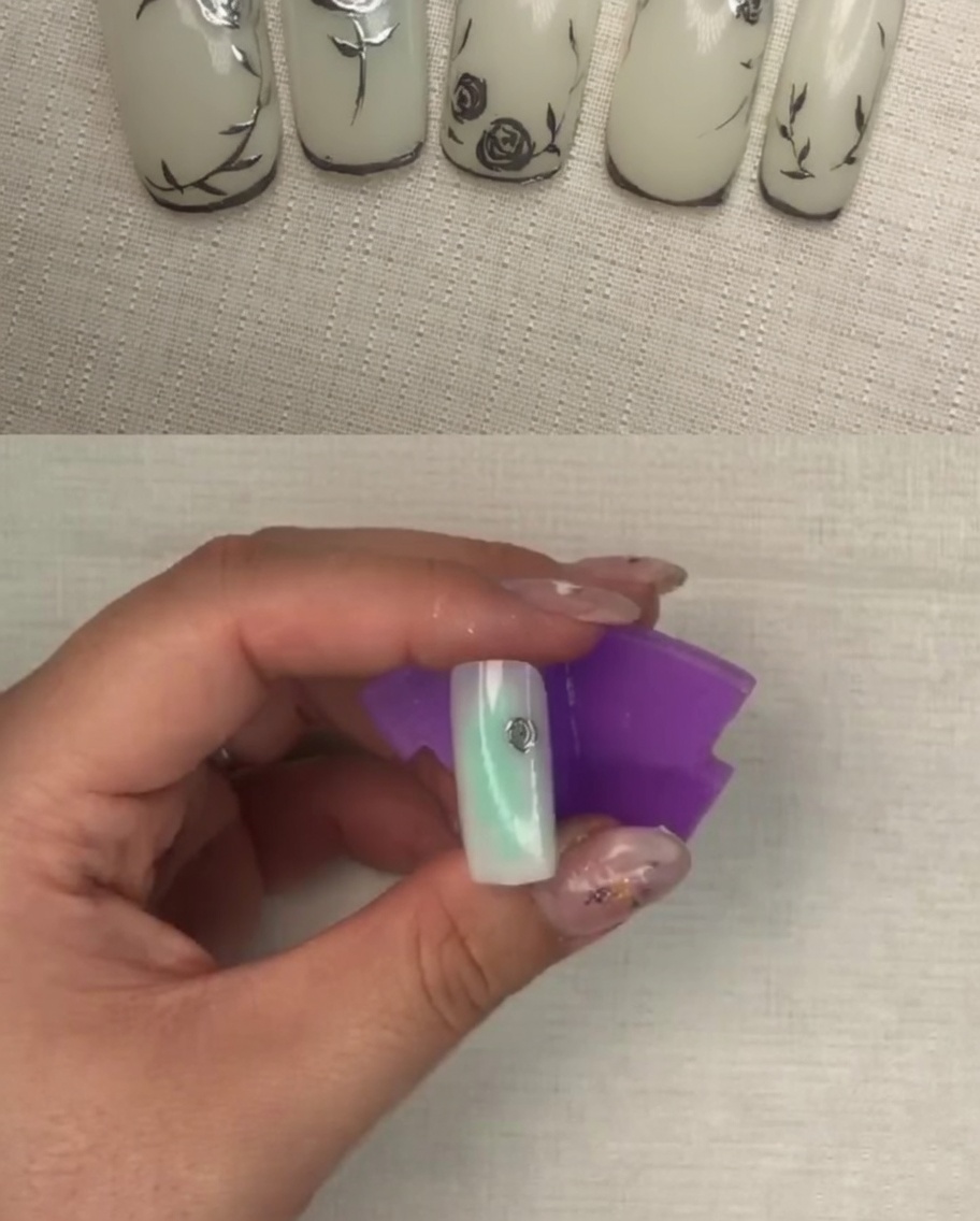 Ein Nagel mit einem ausgeprägteren silbernen Blumendesign mit mehreren Ebenen.