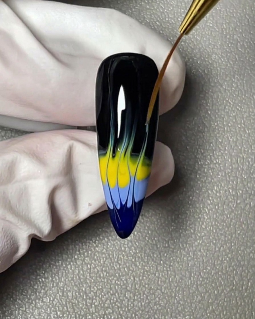 Ein horizontaler Streifen gelber Gel-Lack, der direkt über dem blauen Band auf der Nagelspitze aufgetragen wurde.