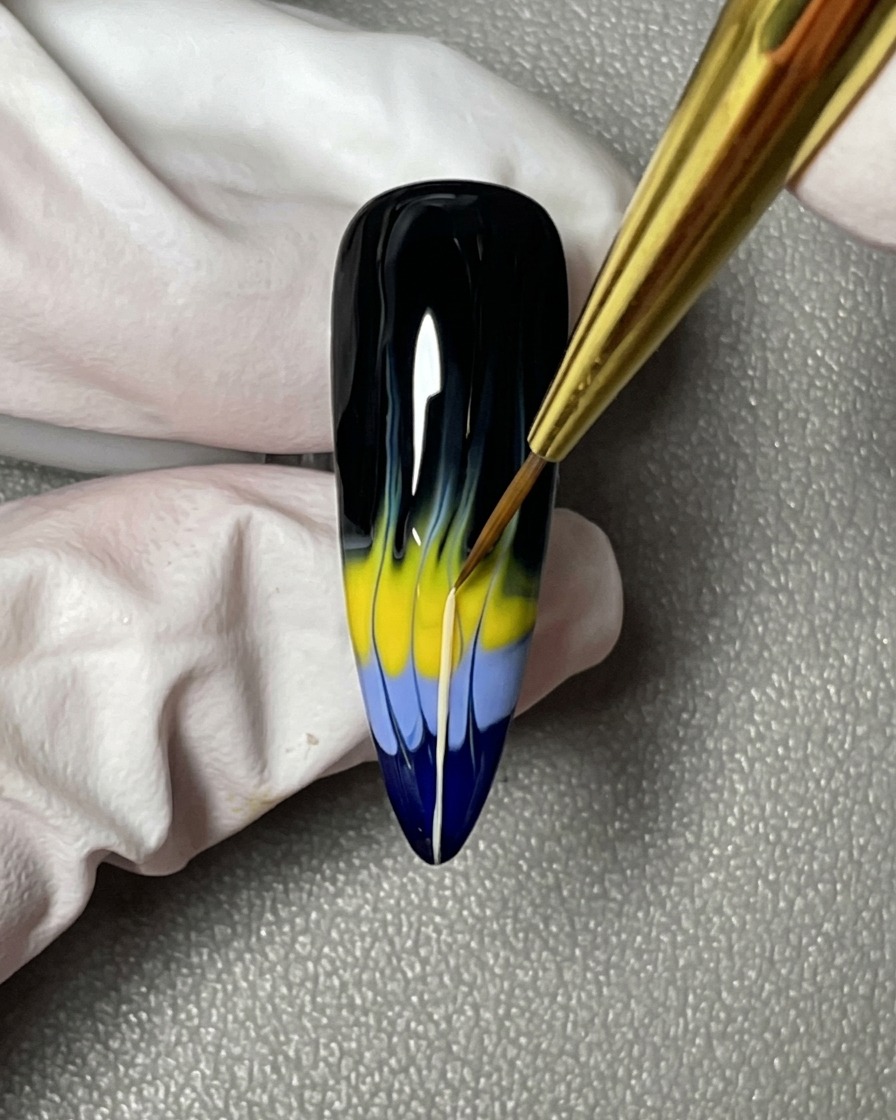 Nahaufnahme eines Nagelpinsels, der dünne Linien von den farbigen Flammenformen in Richtung Nagelwurzel zieht.