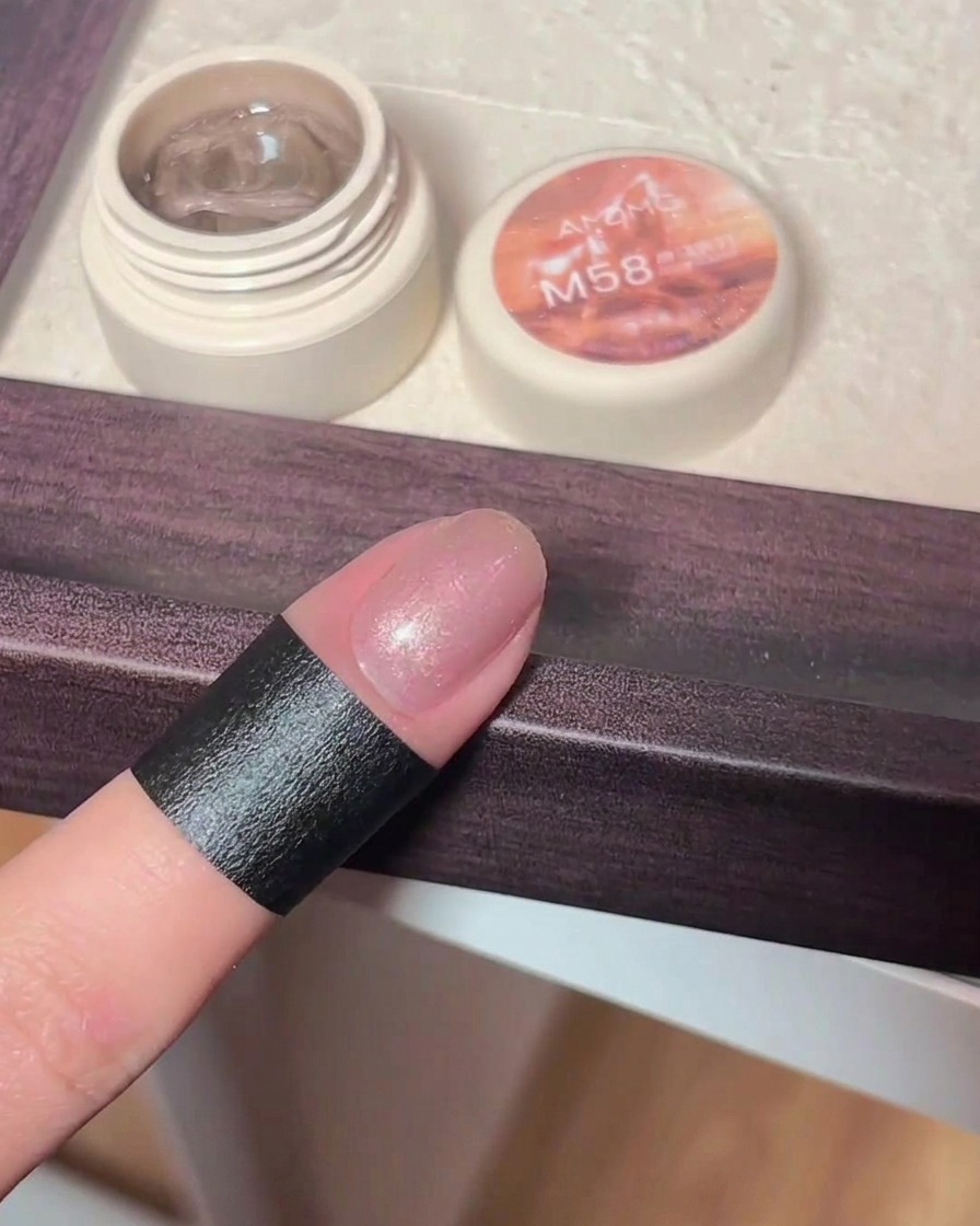 Eine Hand hält einen Magnetstab über einen frisch lackierten Cat-Eye-Gel-Nagel, wobei sich die schimmernden Partikel zu einem Cat-Eye-Muster anordnen.