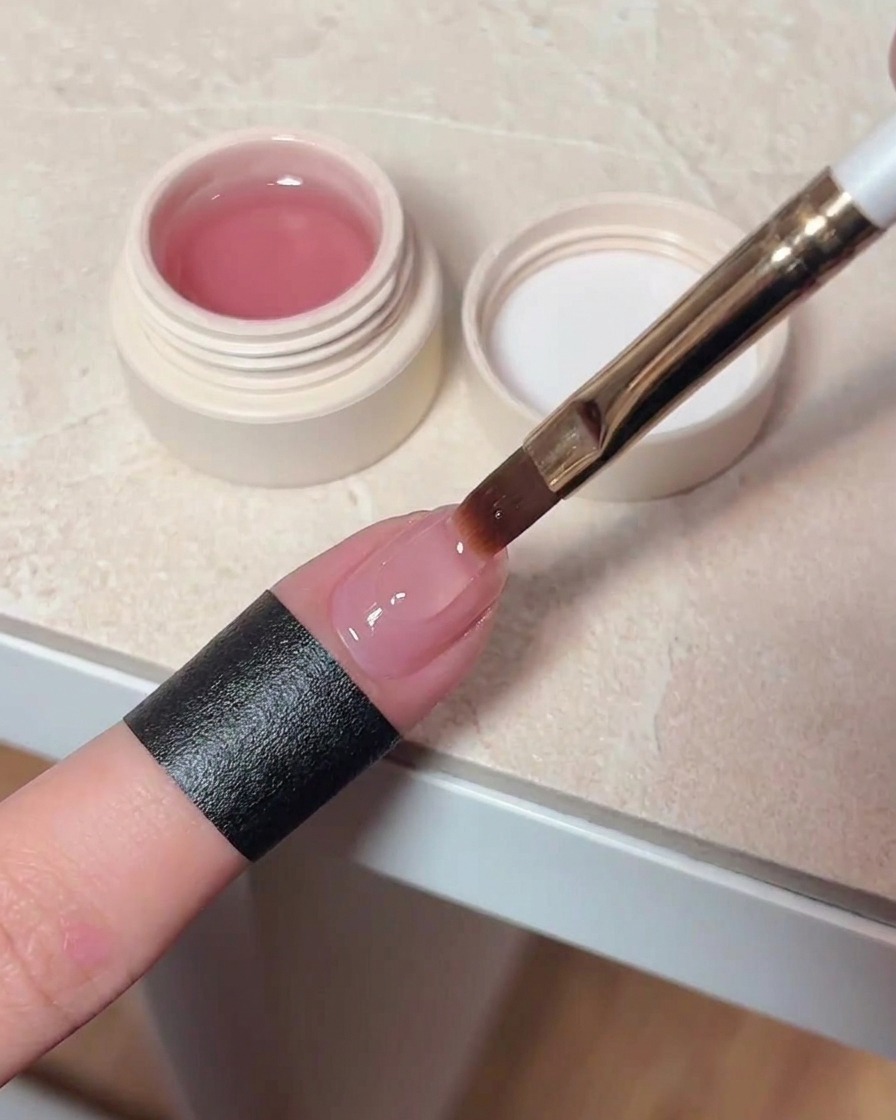Ein Nagellackpinsel trägt einen klaren, glänzenden Top-Coat auf einen ausgehärteten Cat-Eye-Nagel auf.