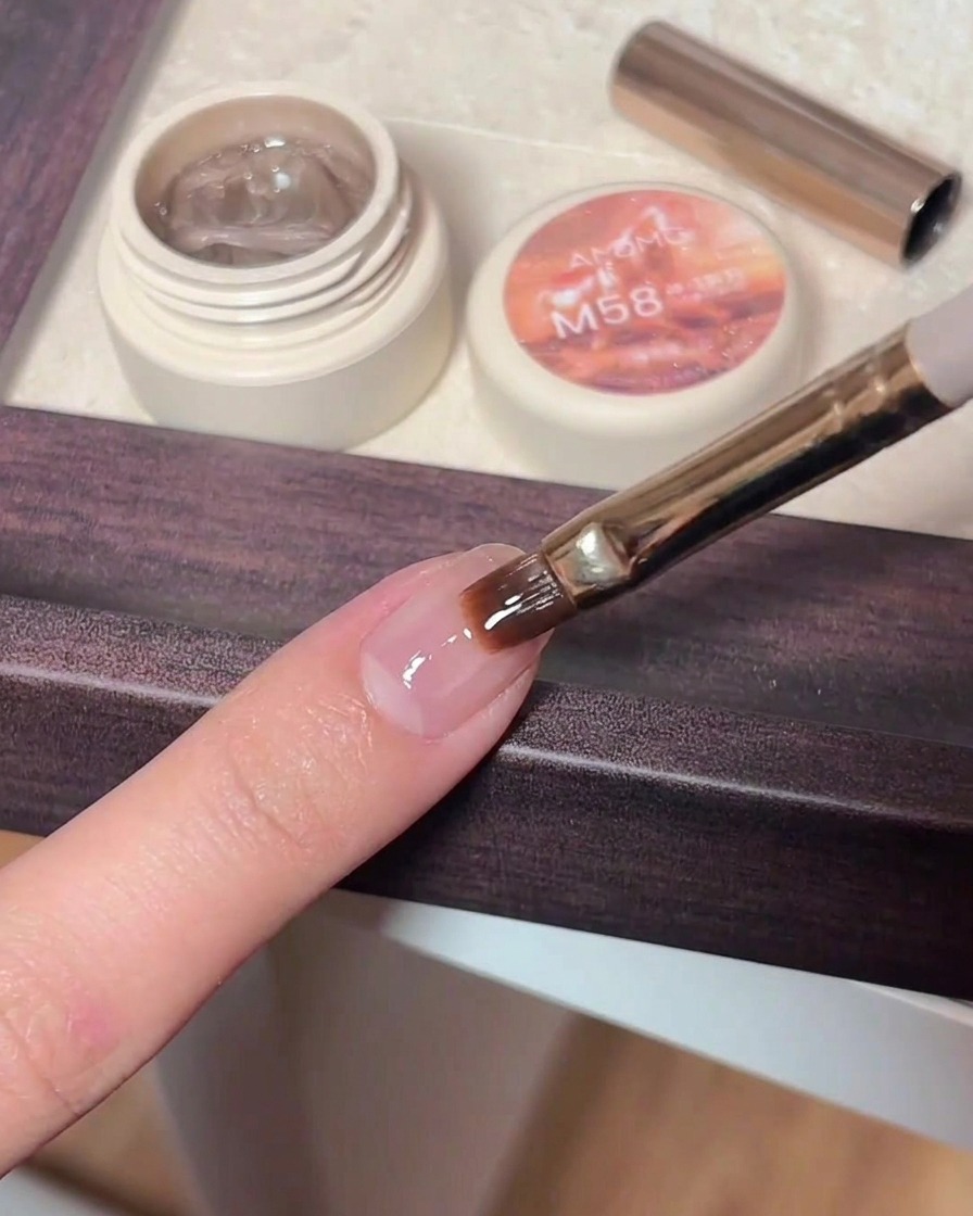 Eine Pinzette platziert ein kleines, glänzendes sternförmiges Glitzerteilchen auf einen Nagel mit feuchtem, klarem Gel-Top-Coat.