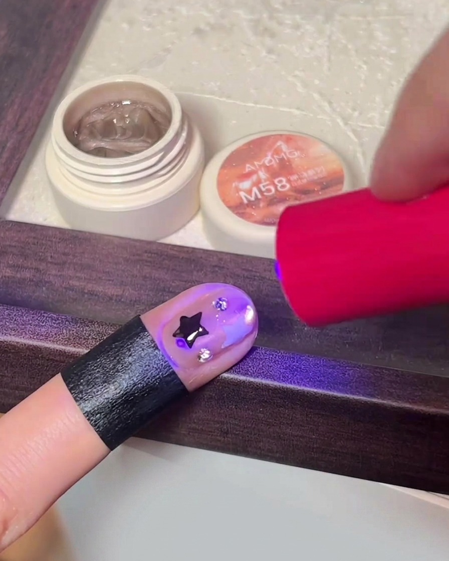 Eine Hand härtet das fertige Nageldesign in einer tragbaren LED-Nagellampe aus.