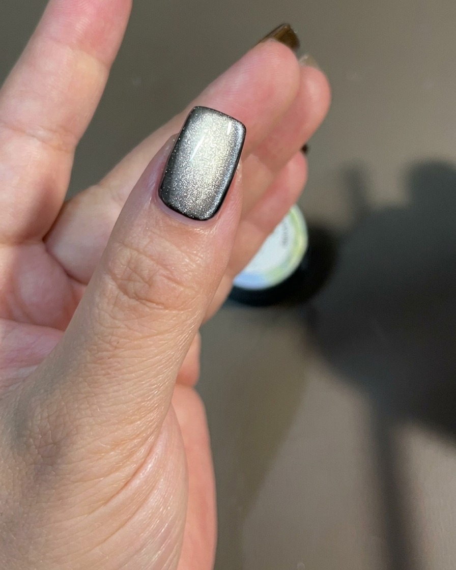 Ein Magnet wird über die Nageloberfläche bewegt, um die schimmernden magnetischen Partikel zu lenken.