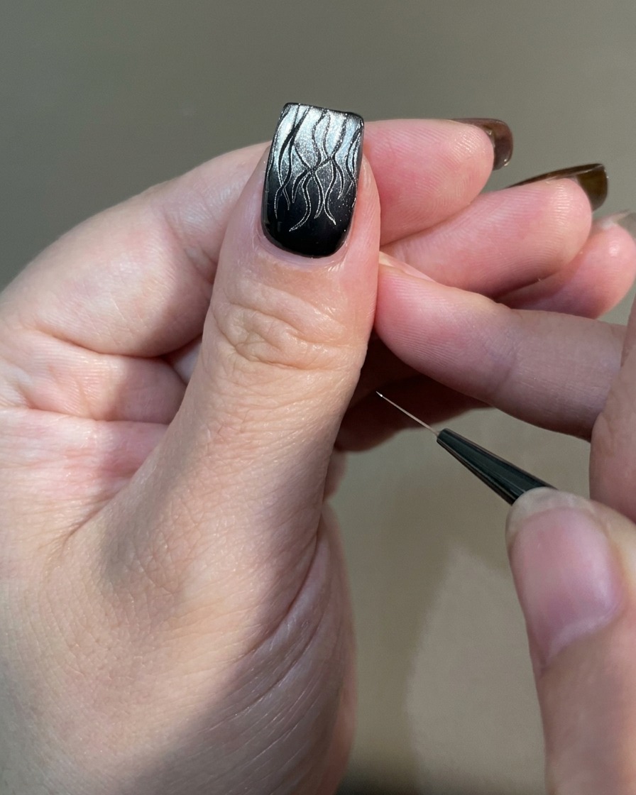Eine Hand mit fertiger Flammen-Nail-Art wird in eine professionelle UV-Nagellampe zum Aushärten gelegt.