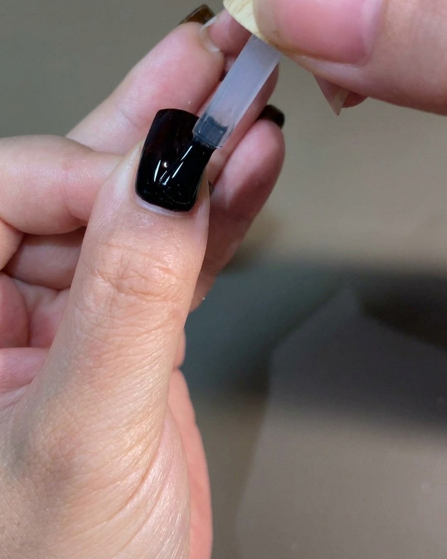 Eine gepflegte Hand härtet die letzte Top Coat Schicht in einer professionellen UV-Nagellampe aus.