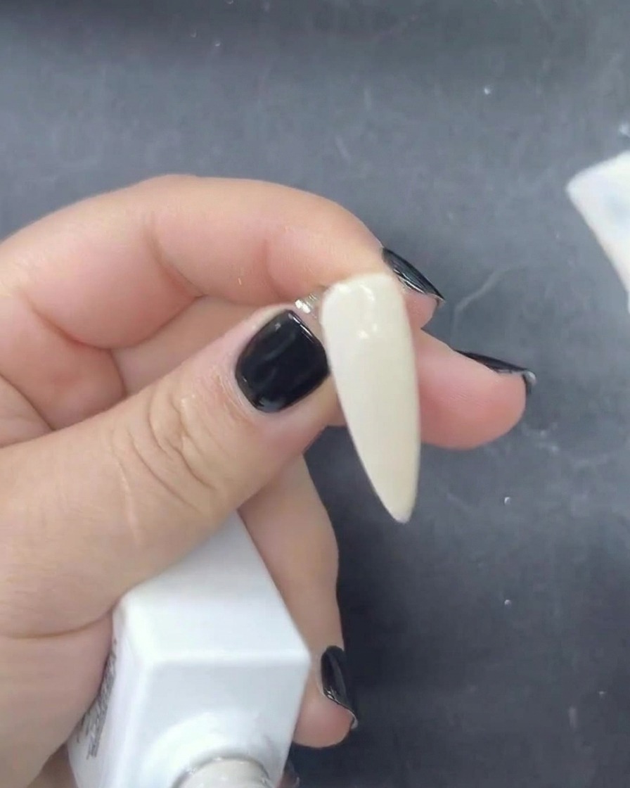Nahaufnahme eines Pinsels, der ein milchig-weißes Gel auf einen Nagel aufträgt.
