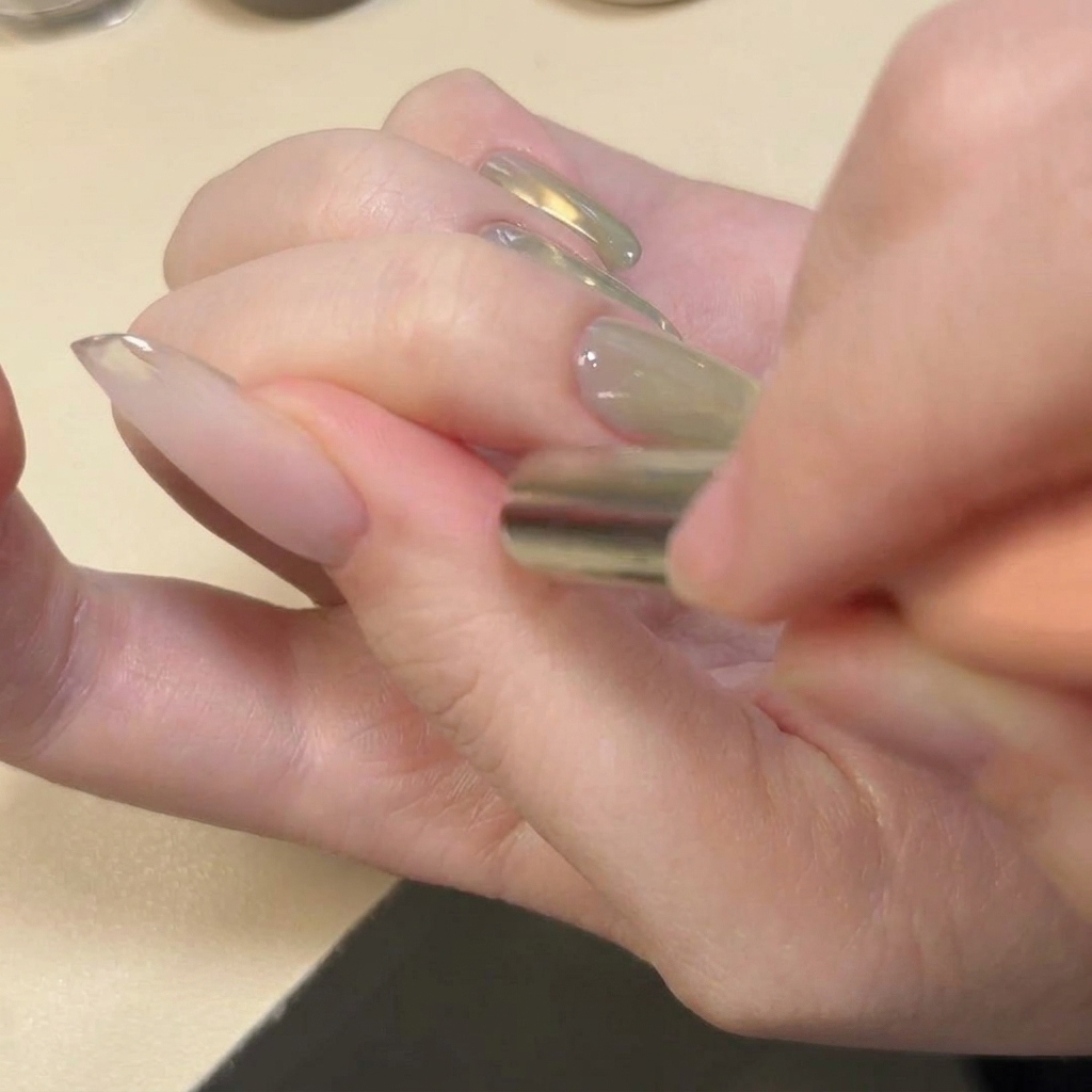 Ein Magnet wird horizontal über die Nagelspitze gehalten, um ein U-förmiges Glitzermuster zu erzeugen.