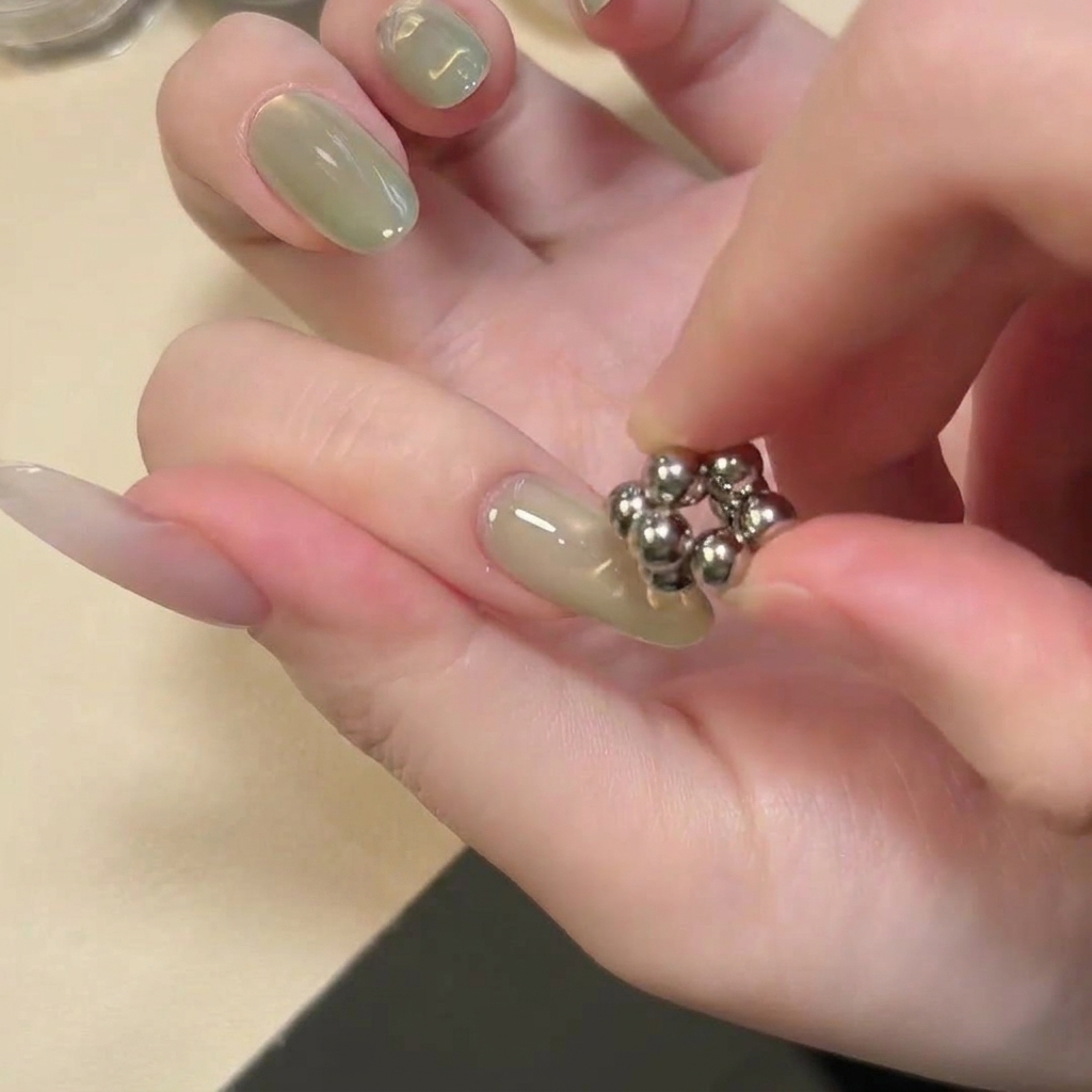 Ein Werkzeug mit kugelförmigen Magneten wird über die Mitte des Nagels gehalten.