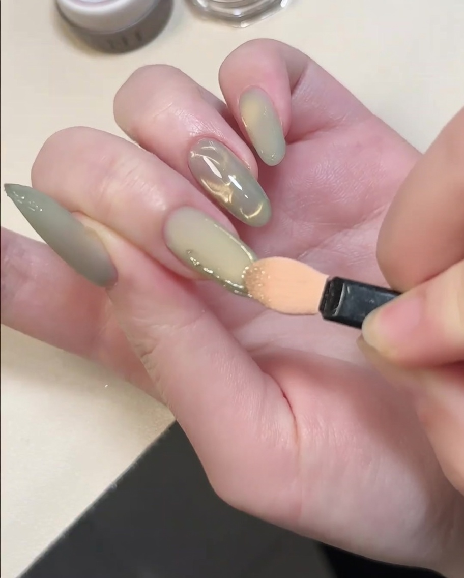 Ein Lidschatten-Applikator reibt goldenes Chrome-Puder auf die erhabenen 3D-Linien.