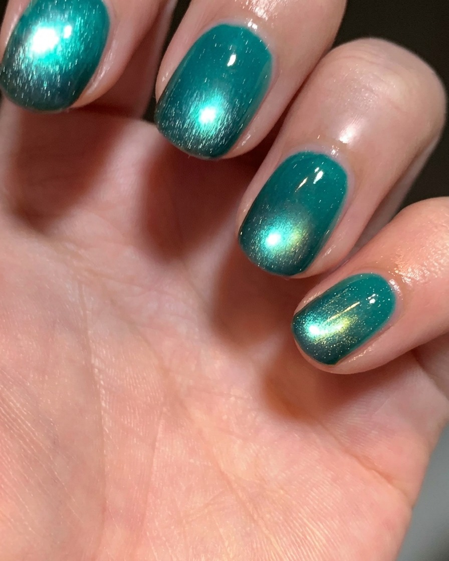 Nahaufnahme einer Fingerspitze, bei der schwarzes Gel mit einem kleinen Kosmetikschwamm auf den Naturnagel aufgetragen wird.