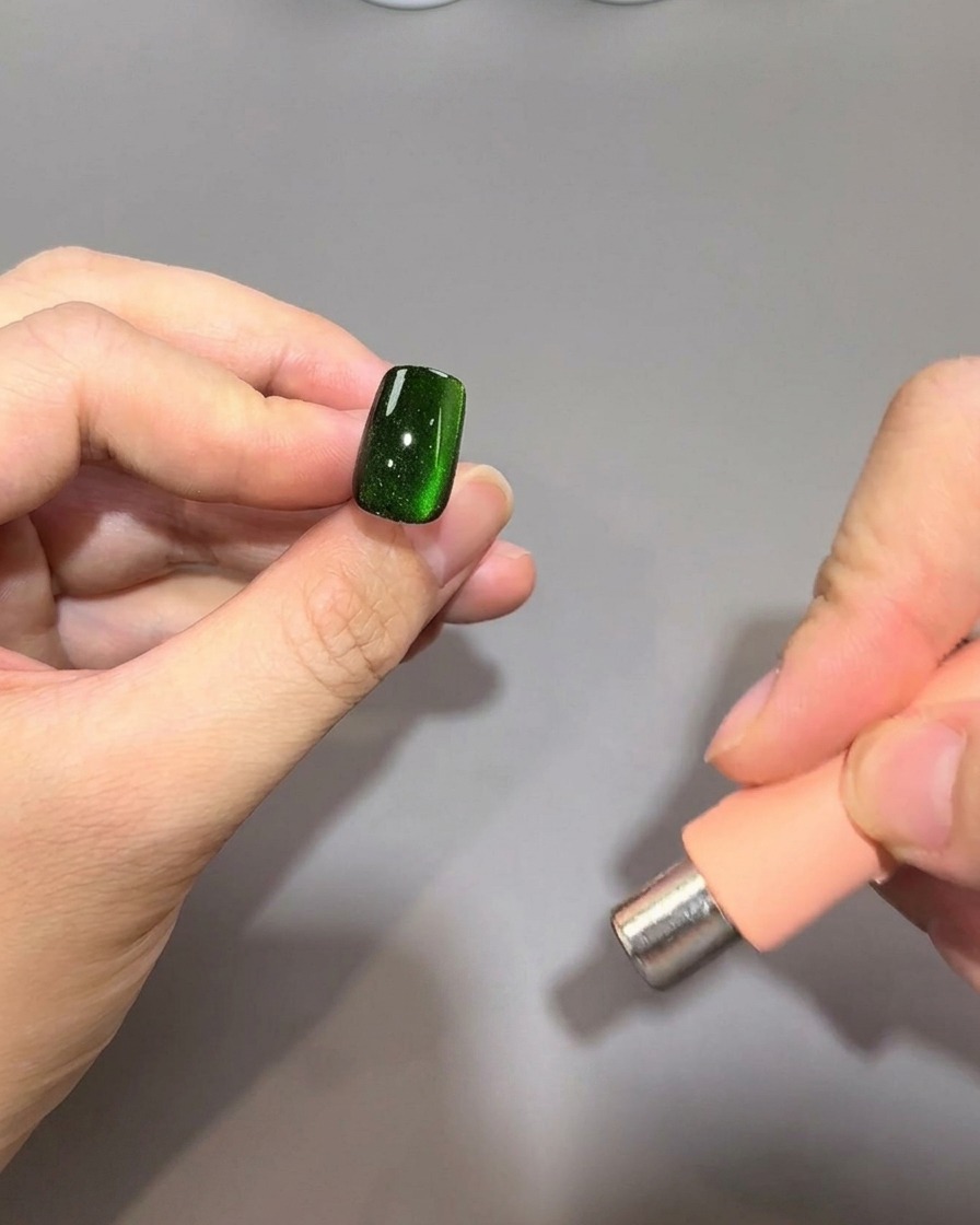 Ein zylindrischer Magnet wird parallel zum rechten Fingernagelrand gehalten, um den magnetischen Glanz weiter zu formen.