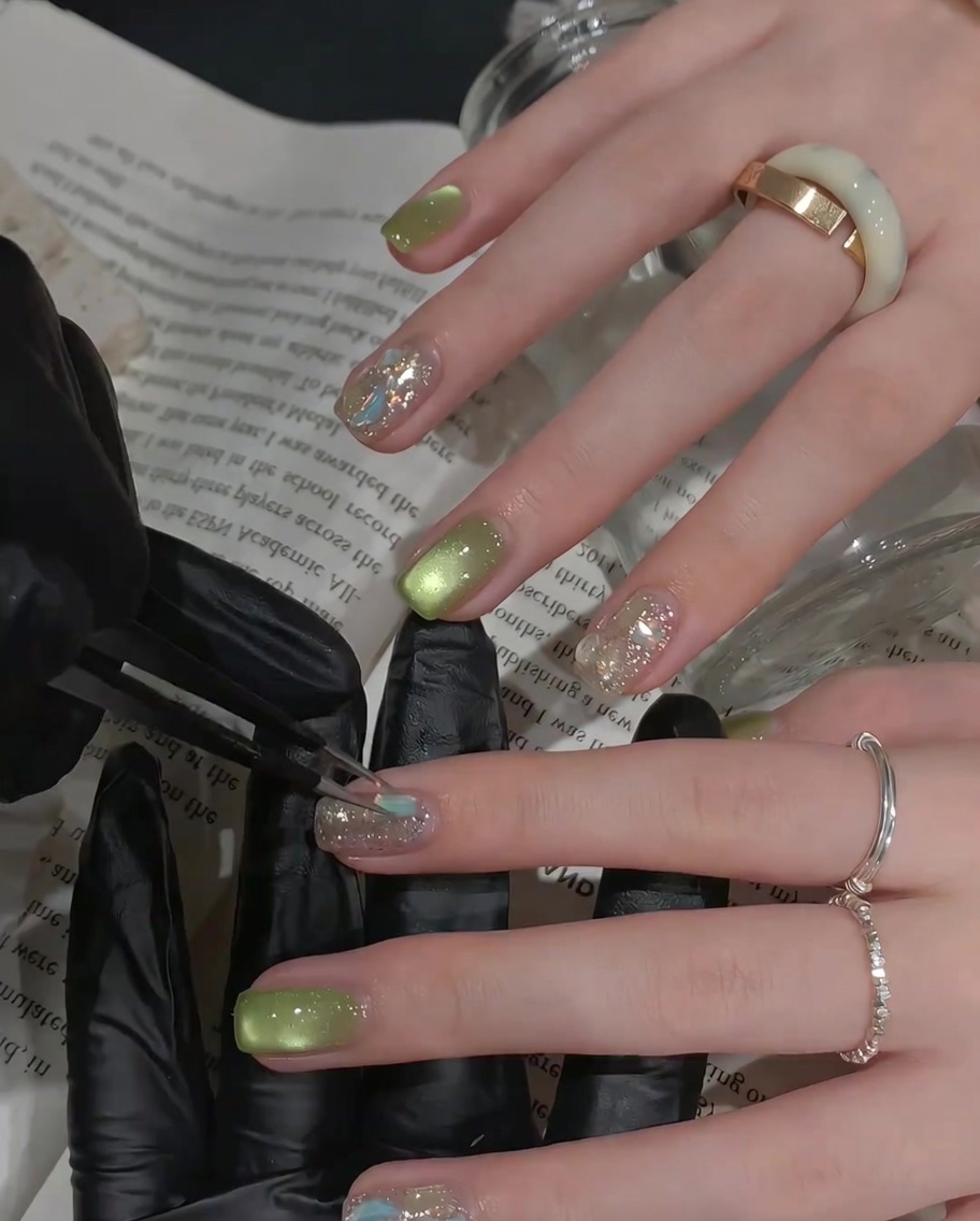 Ein Pinsel trägt einen klaren, glänzenden Top Coat über einen mit Strasssteinen verzierten Akzentnagel auf.