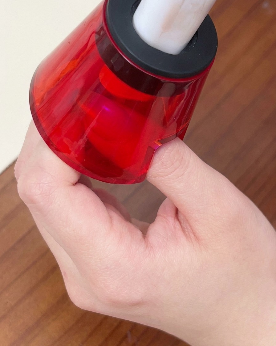 Ein Finger unter einer kleinen roten Hand-LED-Lampe zum Aushärten des Gellacks.