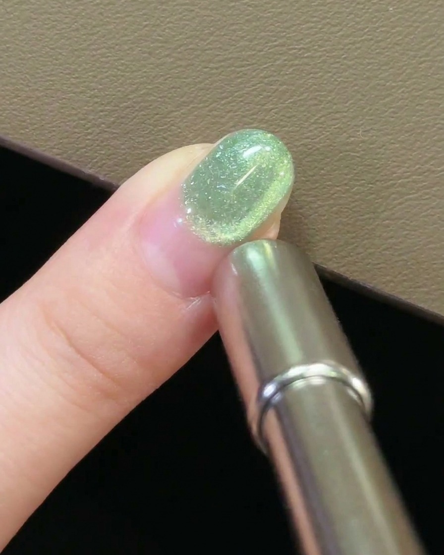 Nahaufnahme eines Magneten, der über einem Nagel schwebt und eine kreisende Bewegung im Cat-Eye-Gel erzeugt.