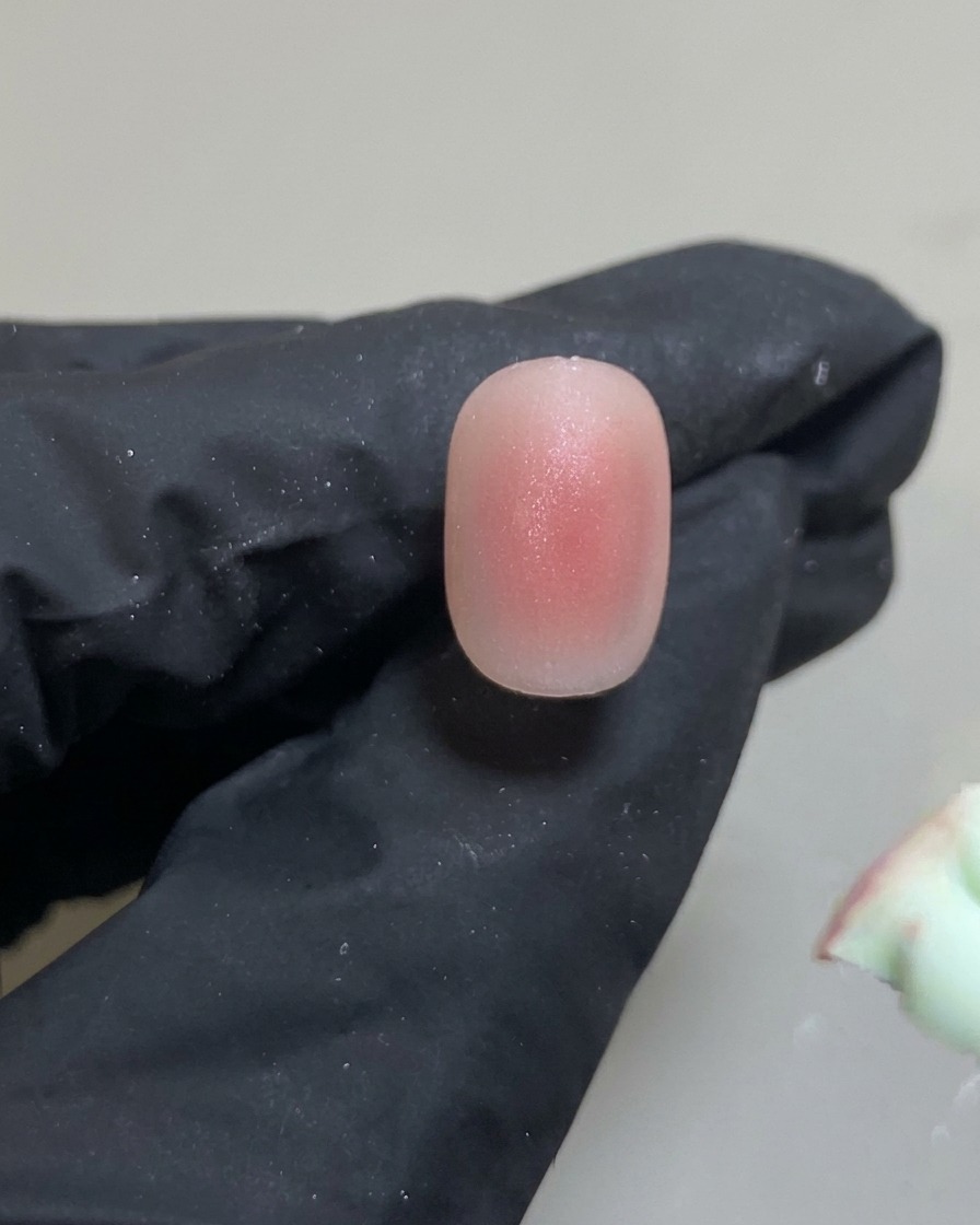 Ein Silikon-Tool platziert einen kleinen, präzisen Punkt rosa Gel in der Nagelmitte.