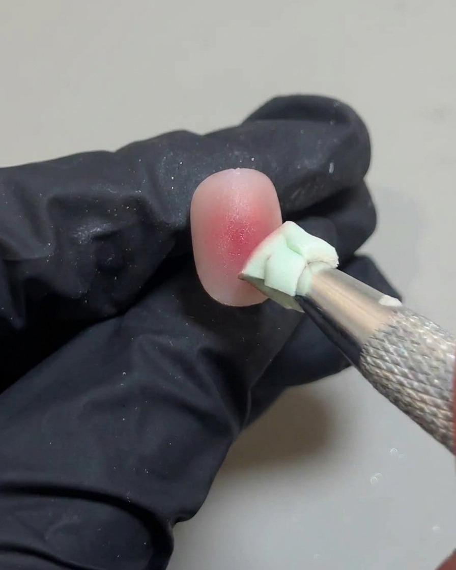 Ein Schwämmchen tupft leicht in der Nagelmitte, um den letzten rosa Geltropfen zu verblenden.