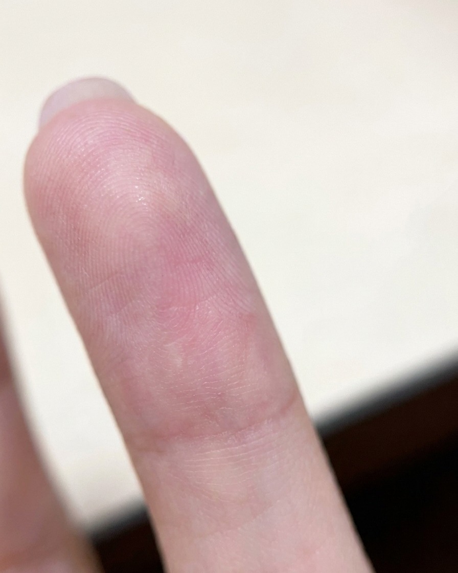 Ein nach unten gedrehter Finger, der ruhig gehalten wird, damit die Schwerkraft das nasse Gel zur Nagelmitte zieht.