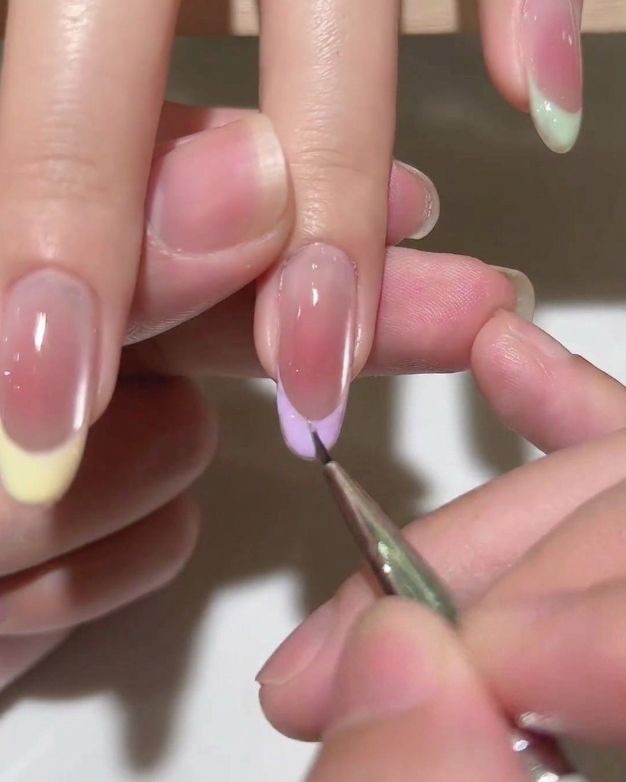 Ein Pinsel trägt eine Schicht klaren Top Coat über die fertige French-Spitze auf.