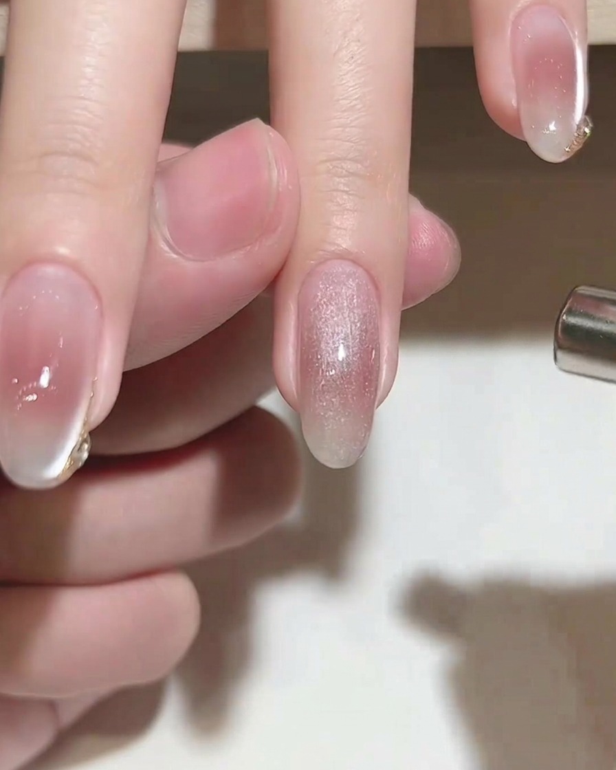 Ein zylindrischer Magnet wird über einen Nagel gehalten, der mit feuchtem Cat-Eye-Gel beschichtet ist, um einen Schimmereffekt zu erzeugen.