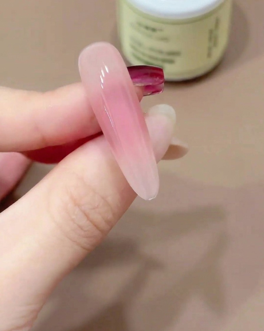 Eine Nagelspitze wird kopfüber gehalten, damit sich der Gel-Topcoat selbst glätten kann.