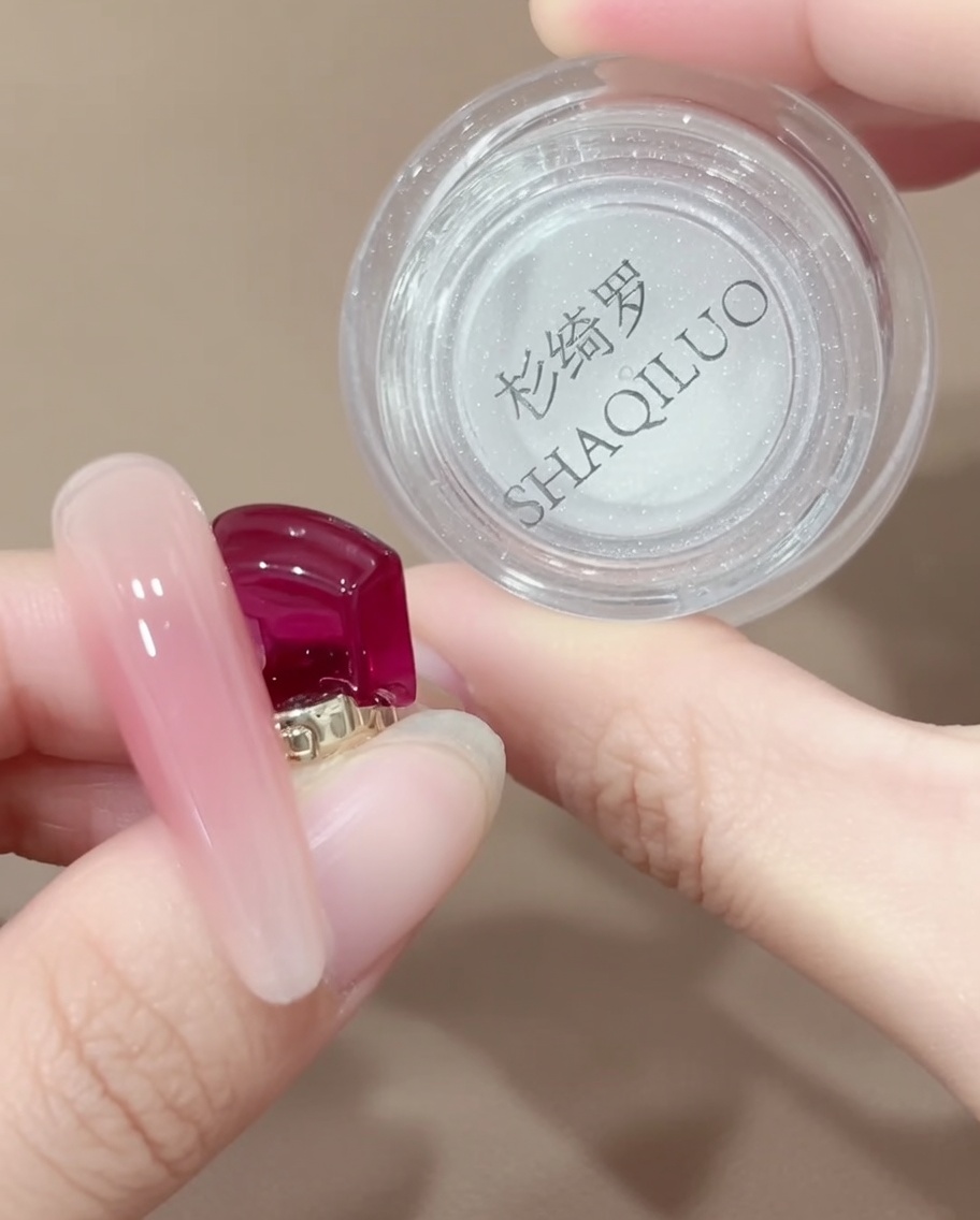 Ein Silikon-Applikator nimmt eine kleine Menge irisierendes Chrome-Puder aus einem Tiegel auf.