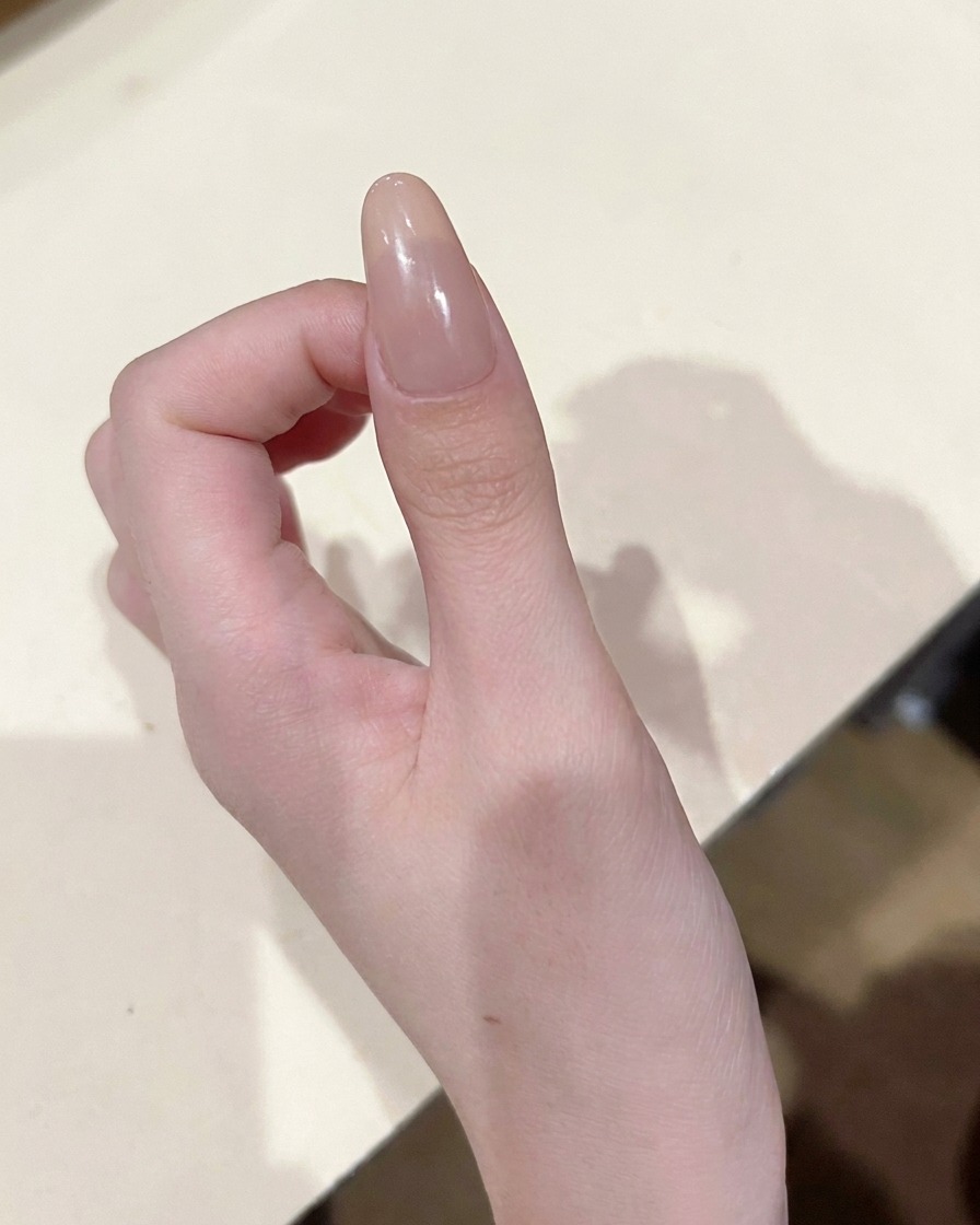 Detailansicht eines Pinsels, der einen kleinen, präzisen Punkt rosafarbenes Farbgel in die Mitte des Nagels setzt.
