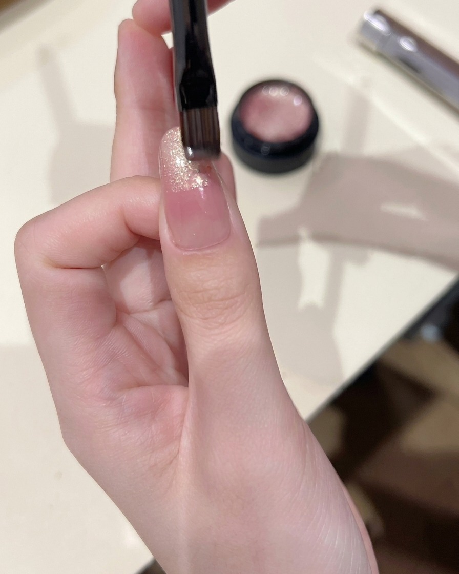 Ein Pinsel trägt Cat-Eye-Gel auf die Nagelspitze auf und verblendet es leicht nach unten.