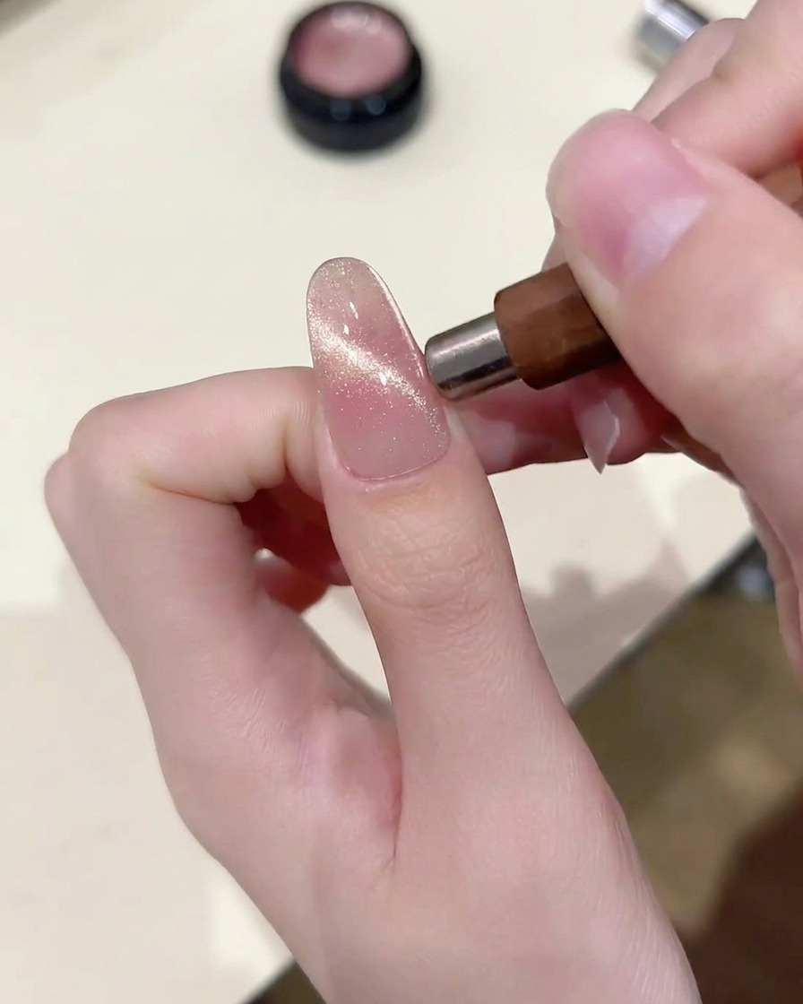 Ein Magnet wird parallel zum Nagel gehalten und zieht die Partikel zu einem horizontalen Lichtband.