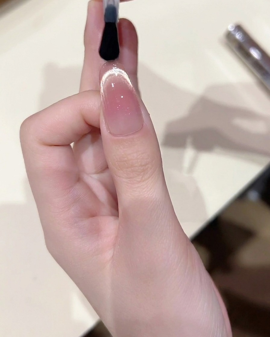 Ein Pinsel versiegelt das fertige Cat-Eye-Design mit einem glänzenden Top Coat.