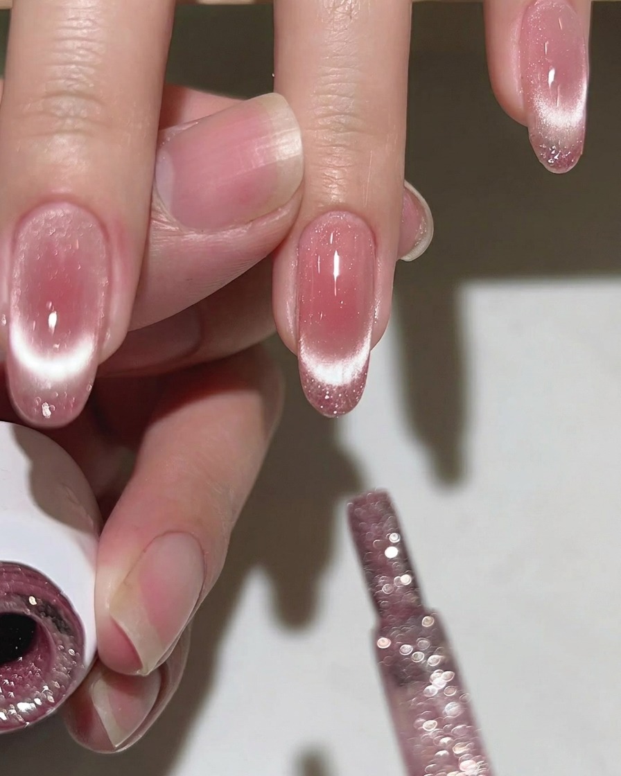 Ein flacher Pinsel wird verwendet, um das rosa Gel auf dem Nagel zu verblenden.
