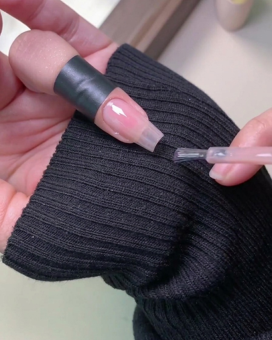 Eine Hand in einer professionellen UV-Nagellampe zum Aushärten des Gellacks.