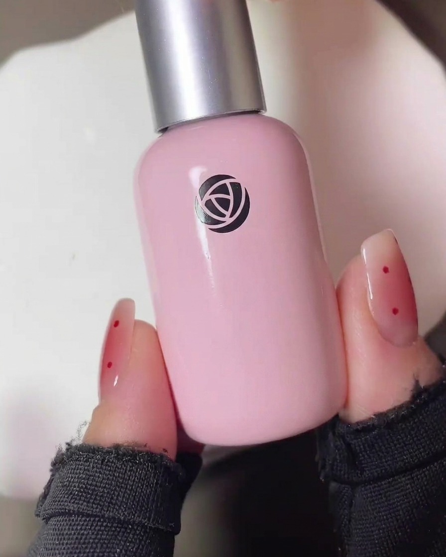 Detailaufnahme eines Pinsels, der eine kleine Menge transparentes rotes Blush-Gel auf die Mitte eines matten Nagels tupft.