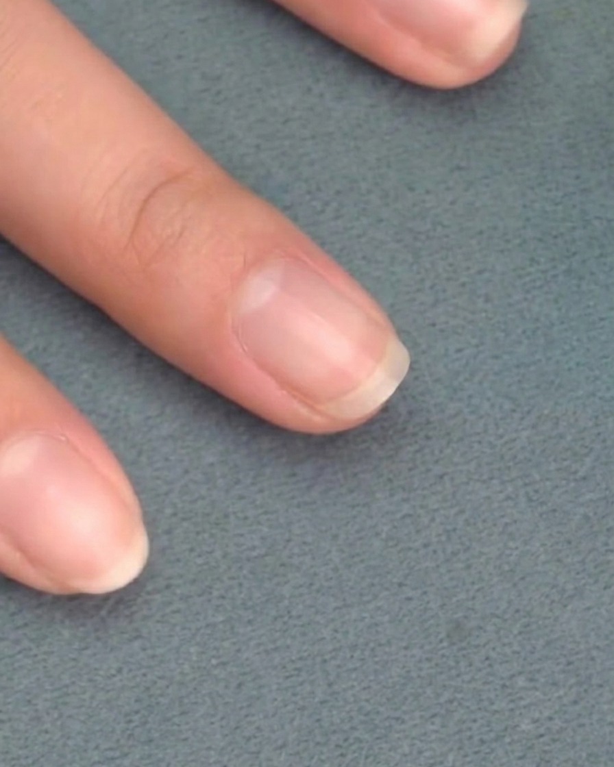 Ein Pinsel trägt zartrosa Gel-Nagellack auf einen vorbereiteten Naturnagel auf.