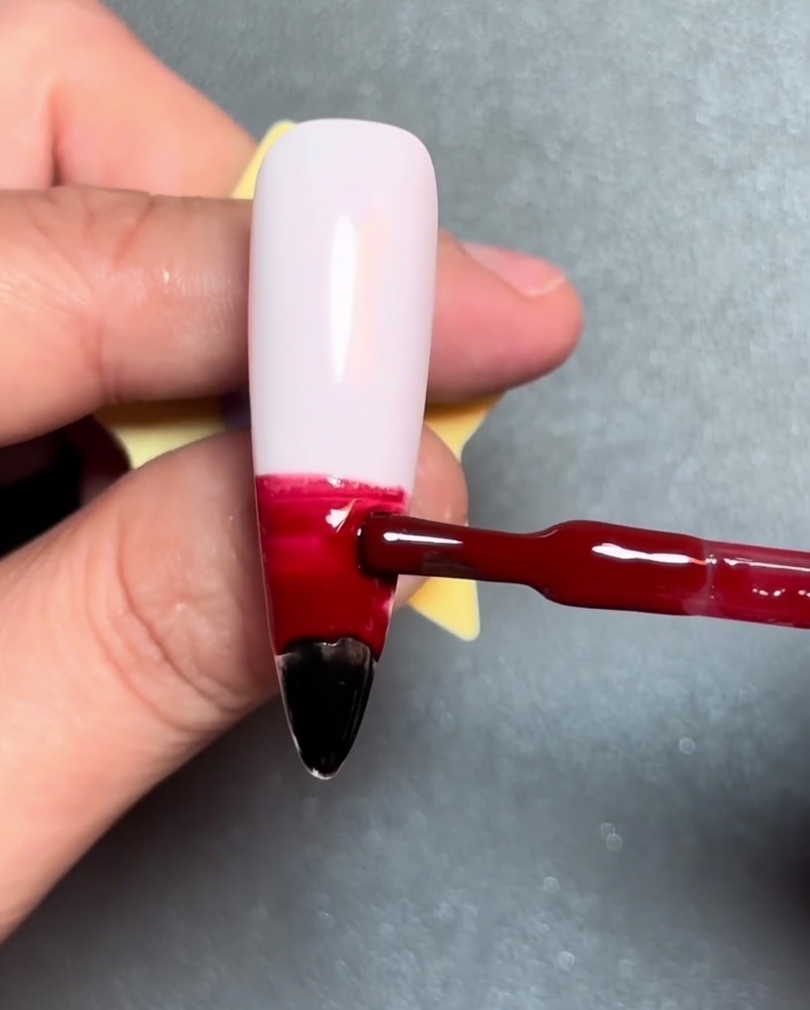 Ein Pinsel trägt einen horizontalen orangen Gelstreifen über dem roten Gel auf.