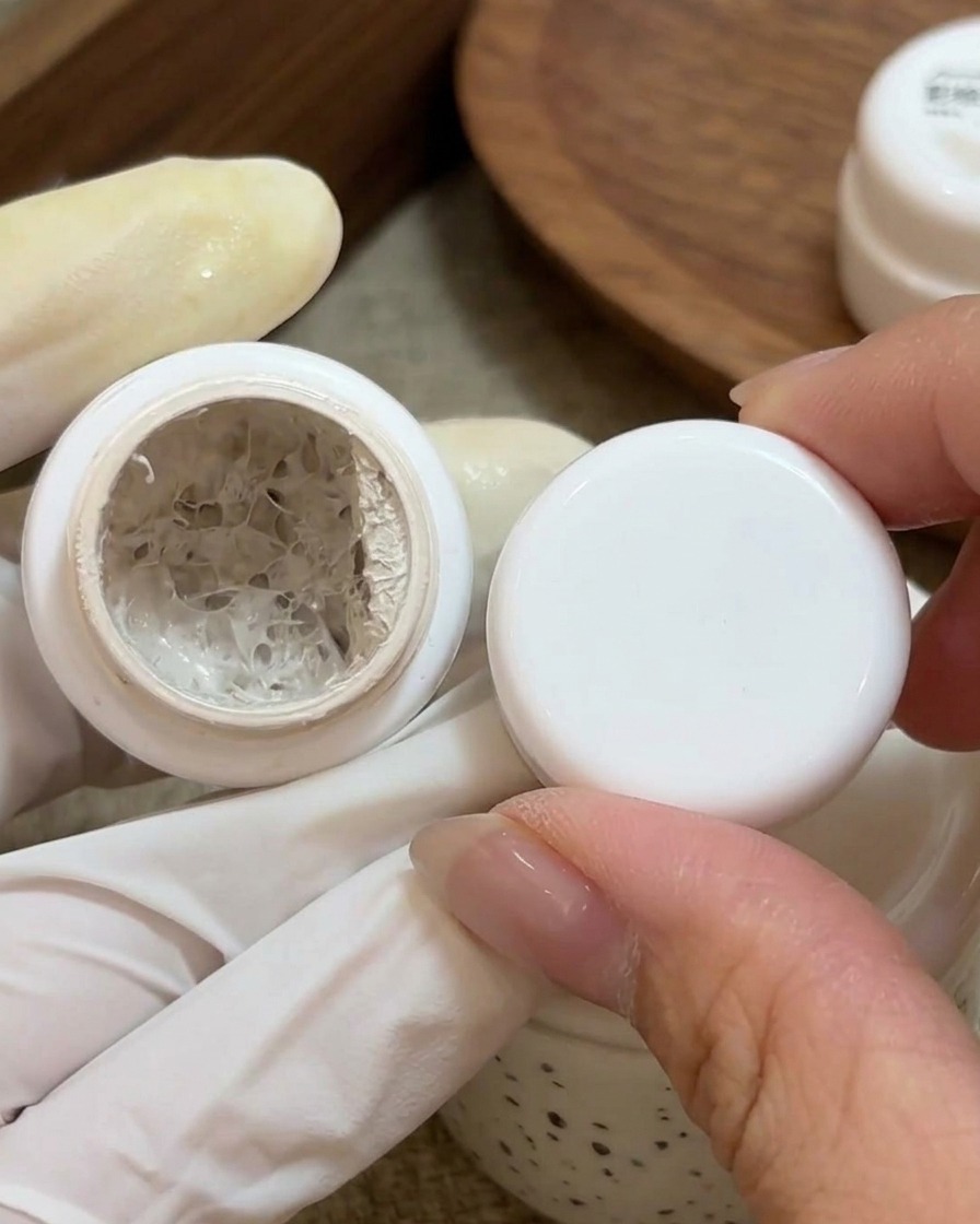 Ein kleiner Pinsel trägt weißes Malgel auf die Basis eines vorbereiteten Naturnagels auf.