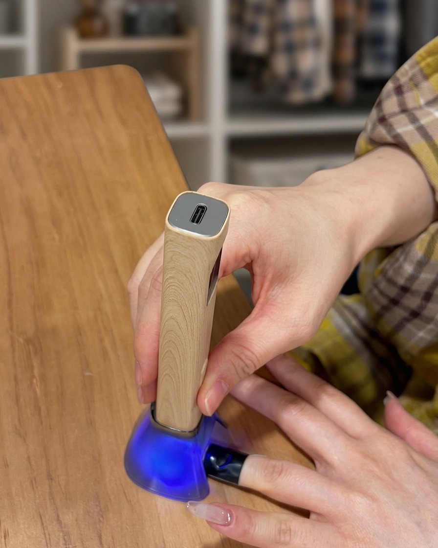 Ein Finger liegt in einer UV-Lampe, während die Top-Coat-Schicht aushärtet.