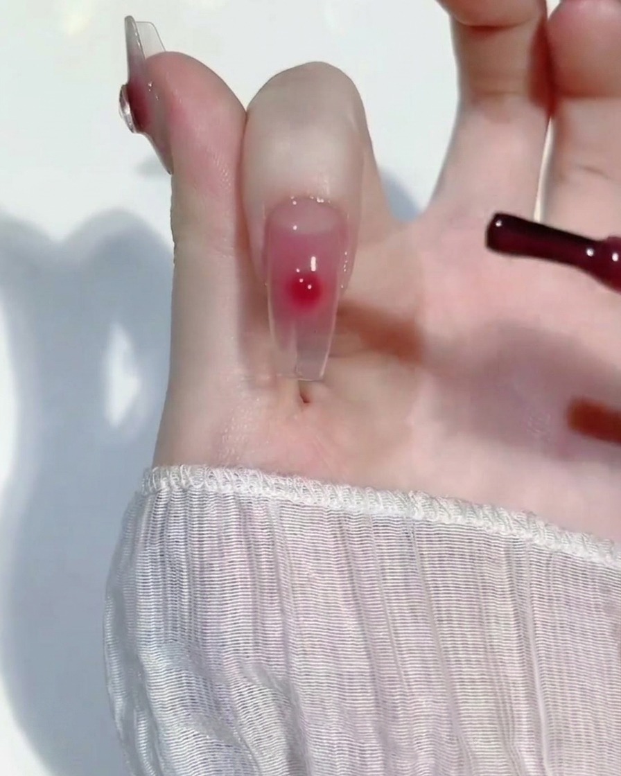 Ein kleiner Tropfen rosa Gel wird mit einem Detailpinsel in die Mitte des Nagels eingearbeitet.