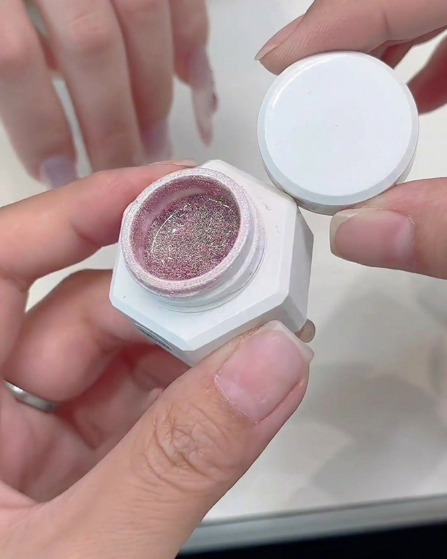 Ein feiner Detailpinsel trägt silbernes Glitzergel entlang der Kante einer Cat-Eye French-Spitze auf.