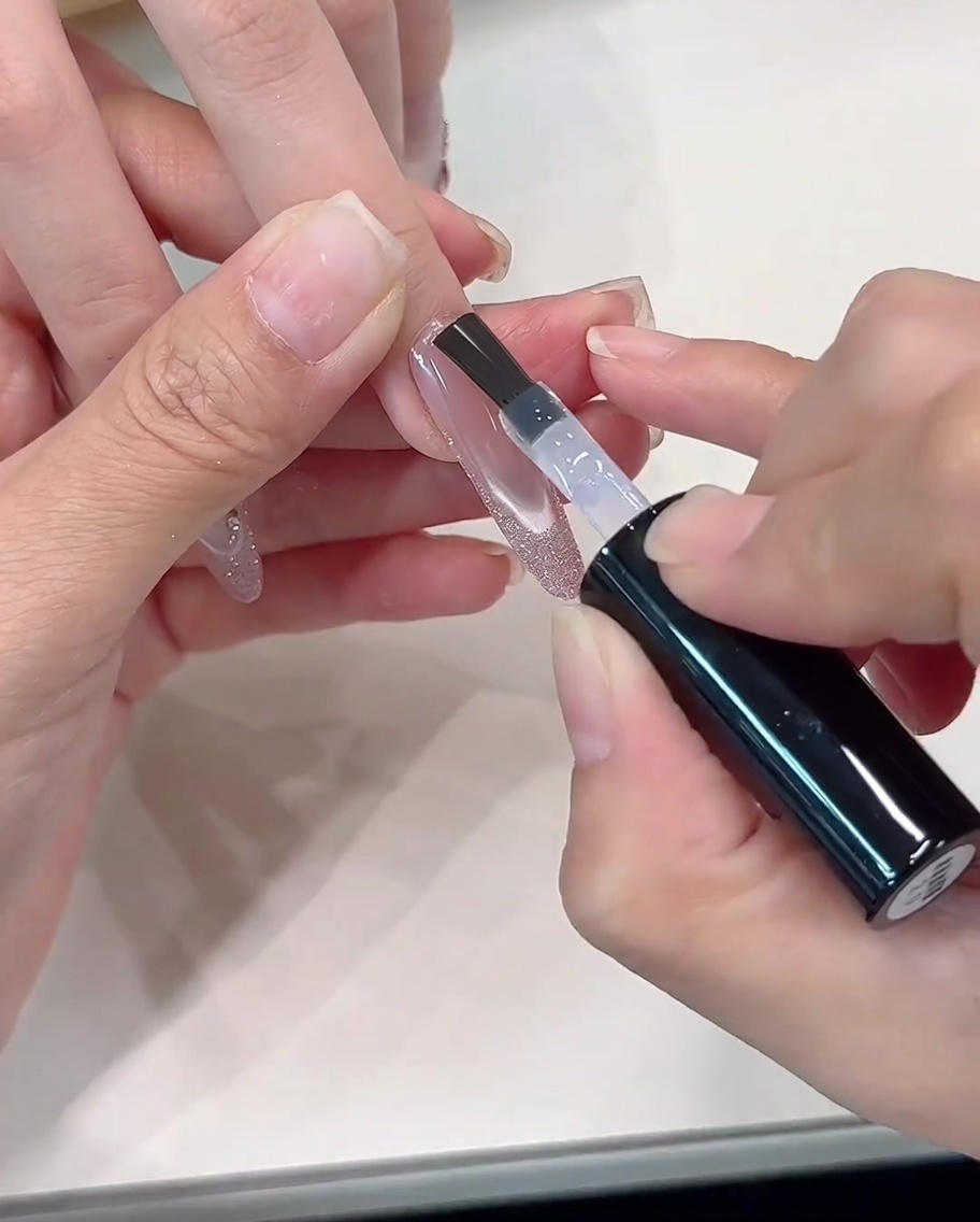 Ein klares Versiegelungsgel wird über das fertige Glitzer-French-Design aufgetragen.