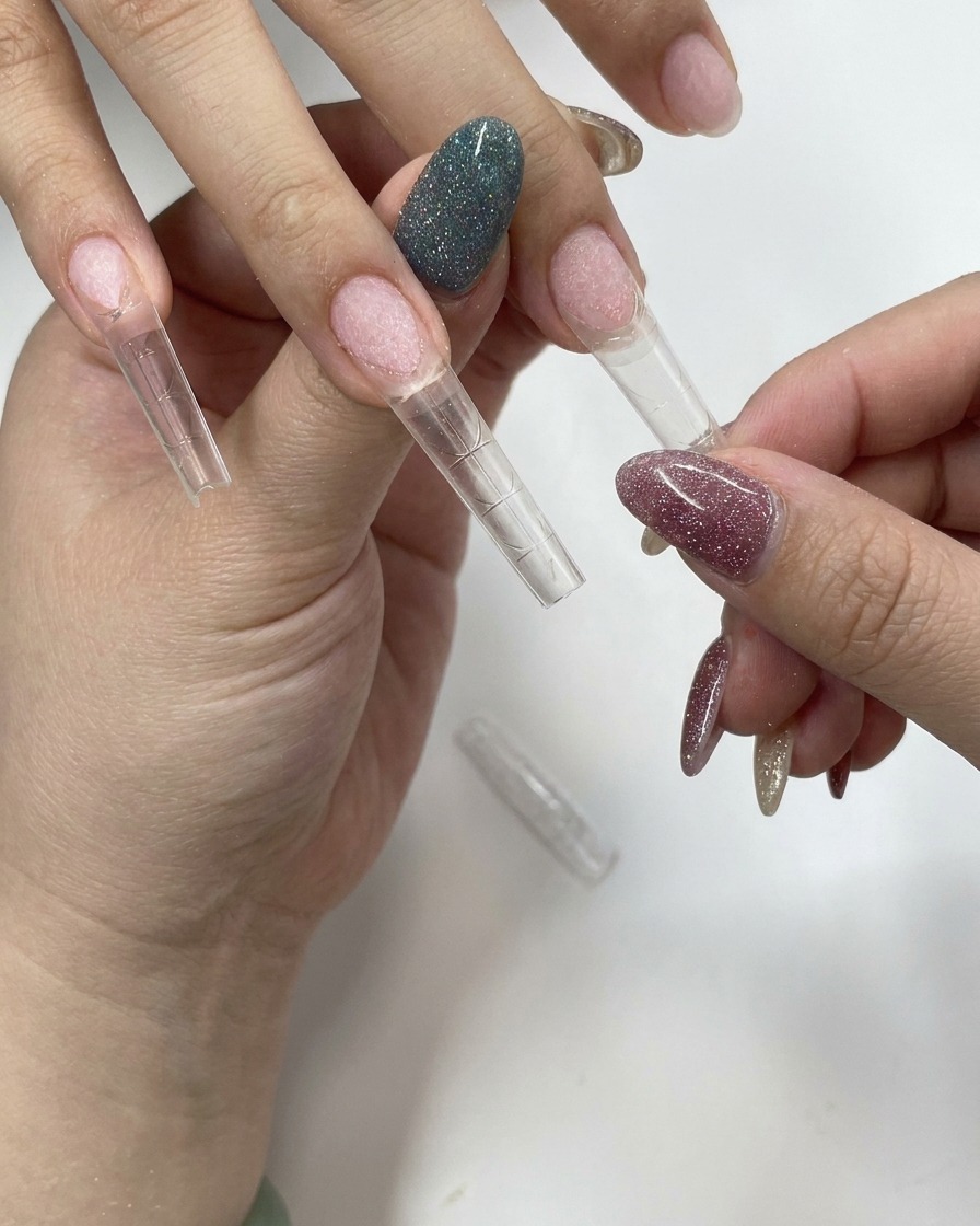 Eine Hand drückt fest einen transparenten Nageltip auf einen Naturnagel.